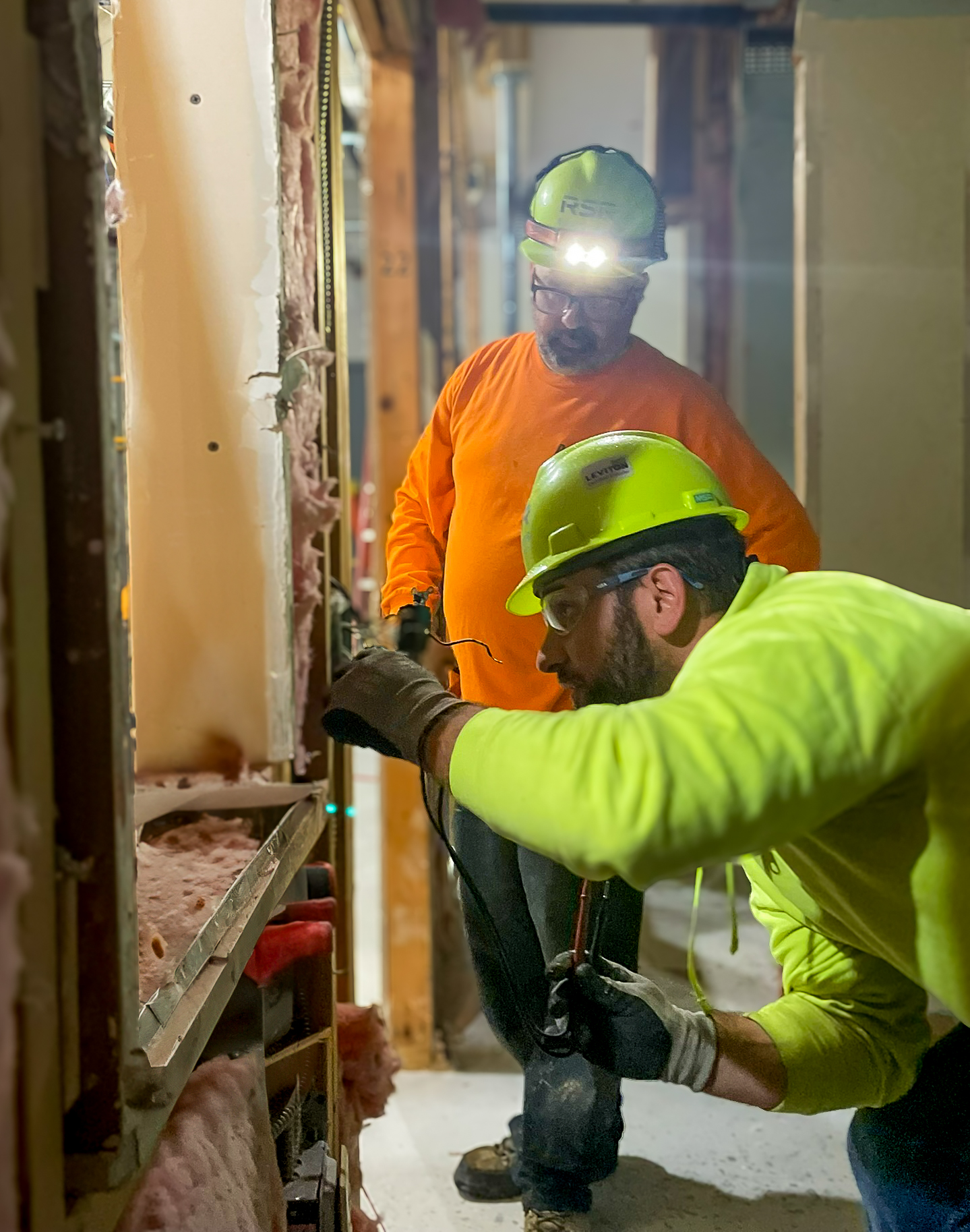 Electricians installing wiring within wall renovations